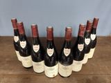 six bottles of wine are lined up on a wooden table