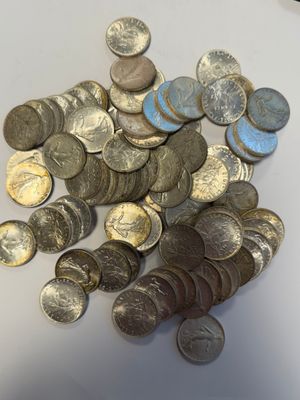 une pile de pièces de monnaie posée sur une table à côté d'un téléphone portable