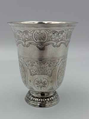 une tasse en argent antique avec un motif floral sur le bord