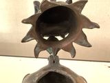 a metal vase with a sun on top of it