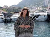 une femme enceinte debout sur un quai devant un port de plaisance