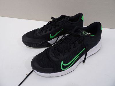 des chaussures de course Nike noires et vertes posées sur une surface blanche