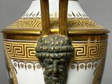 a gold and white vase with a lion head on it