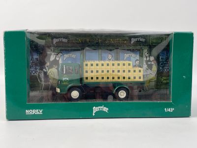 un petit camion jouet vert et jaune dans une boîte verte posée sur une surface blanche