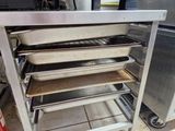 several pans of food sit on a metal rack in a kitchen
