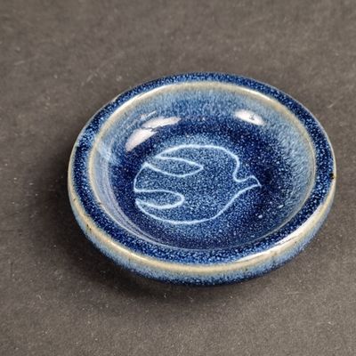 a blue plate with a bird on it on a table