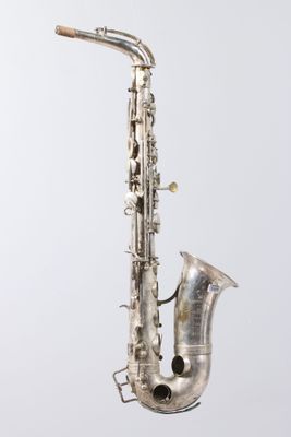 an old silver saxophone sitting on top of a white surface