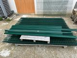 une pile de grilles métalliques vertes posées sur une palette en bois