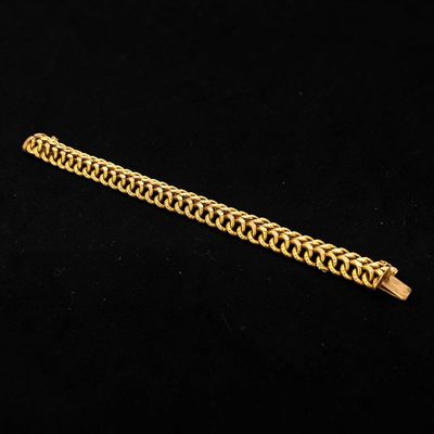 a close up of a gold chain bracelet on a black background