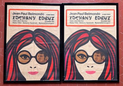 deux affiches représentant une femme aux cheveux roux et portant des lunettes, accrochées sur un mur rouge