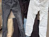 Plusieurs paires de jeans sont empilées sur des cartons dans un entrepôt