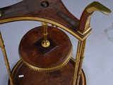 a wooden and brass clock on a stand on a table