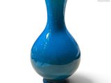 un vase bleu posé sur une surface blanche