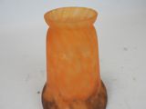 a small orange vase sitting on top of a white table