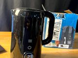 une cafetière noire posée sur une table à côté d'un ordinateur portable