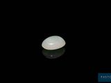 an oval white jade stone on a black surface