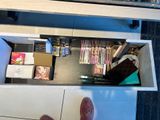 a person standing at a desk with a drawer full of books