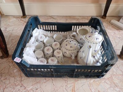 un panier rempli de théières et de tasses posé par terre