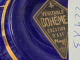 a blue glass plate with a gold trim and a label on it