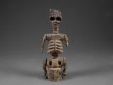 une figurine en bois représentant un squelette assis sur une charrette