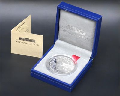an image of a silver coin with a red ribbon in a blue box
