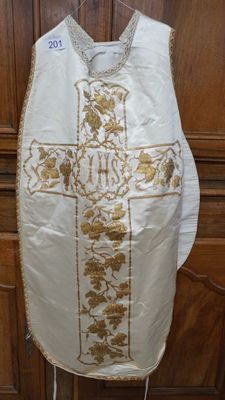 un gilet blanc orné d'une croix dorée, accroché à un mur en bois