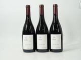 trois bouteilles de vin rouge posées l'une à côté de l'autre sur une surface blanche