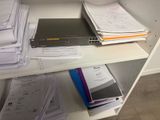 une étagère sur laquelle se trouvent une pile de papiers et un ordinateur portable