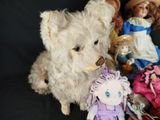 a teddy bear sitting next to a pile of dolls