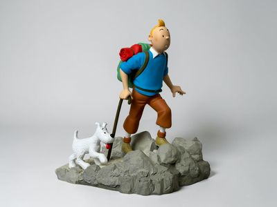 figurine of a man with a backpack and a dog on a rock