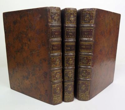 two old books are stacked on top of each other on a white surface