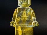 yellow lego man with chanel logo on it standing in front of a black background