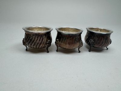three small metal pots sitting next to each other on a white surface