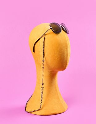 une tête de mannequin portant des lunettes de soleil sur un fond rose