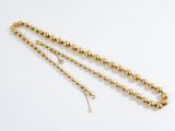 a close up of a gold beaded necklace on a white background
