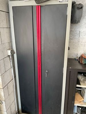 a red pipe sticking out of the door of a metal cabinet