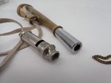 two metal whistles on a white table with a gold chain