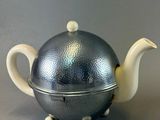 a silver teapot with a silver lid on a table