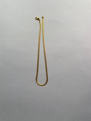 un collier en or dont l'extrémité est ornée d'une longue chaîne