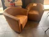 une paire de fauteuils en cuir marron placés dans une pièce près d'une fenêtre
