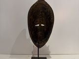 an image of a wooden mask on a stand in front of a white wall