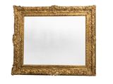 un grand miroir à cadre doré, orné d'un motif décoratif sur fond blanc