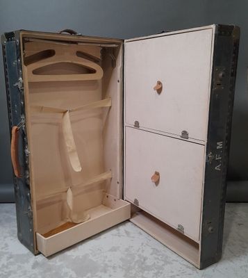 an open suitcase with a tie in it sitting on the floor