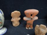 several pieces of pottery sitting on a black surface next to a vase