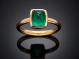 a close up of a gold ring with an emerald stone