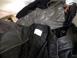 a black leather jacket and a black leather jacket on a bed