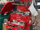 une boîte à outils rouge posée à côté d'une poubelle verte dans un garage
