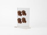 un présentoir en acrylique transparent sur lequel sont disposés trois beignets au chocolat