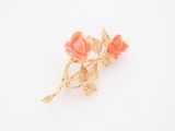 broche en forme de fleur plaquée or, ornée de fleurs roses sur fond blanc