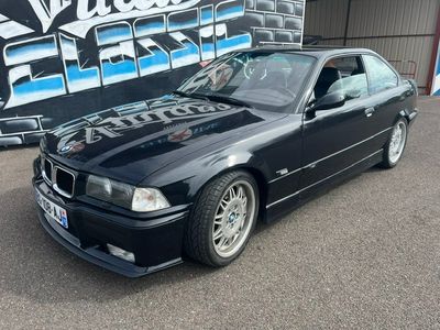 une photo d'une BMW noire garée devant un immeuble